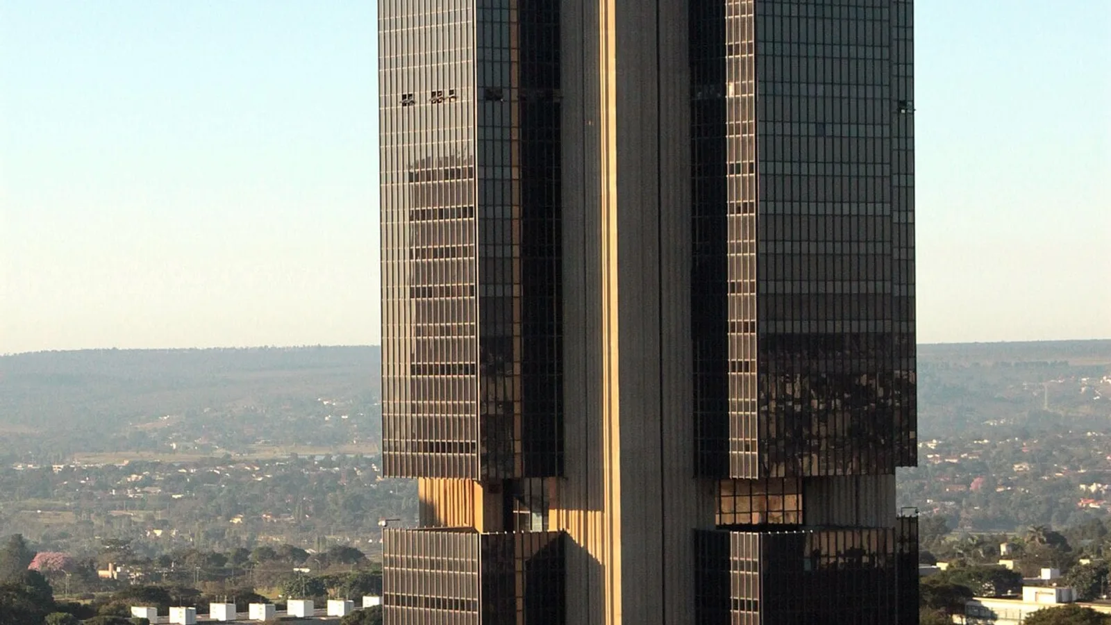 Edifício-sede do Banco Central, em Brasília, com fachada de vidro escuro e céu azul ao fundo