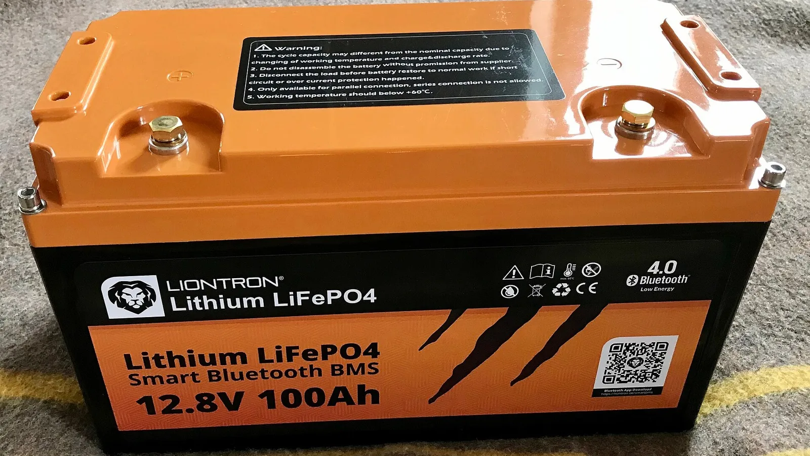 Bateria LiFePO4 de 12,8 V e 100 Ah com caixa laranja e preta, com a química escrita na etiqueta