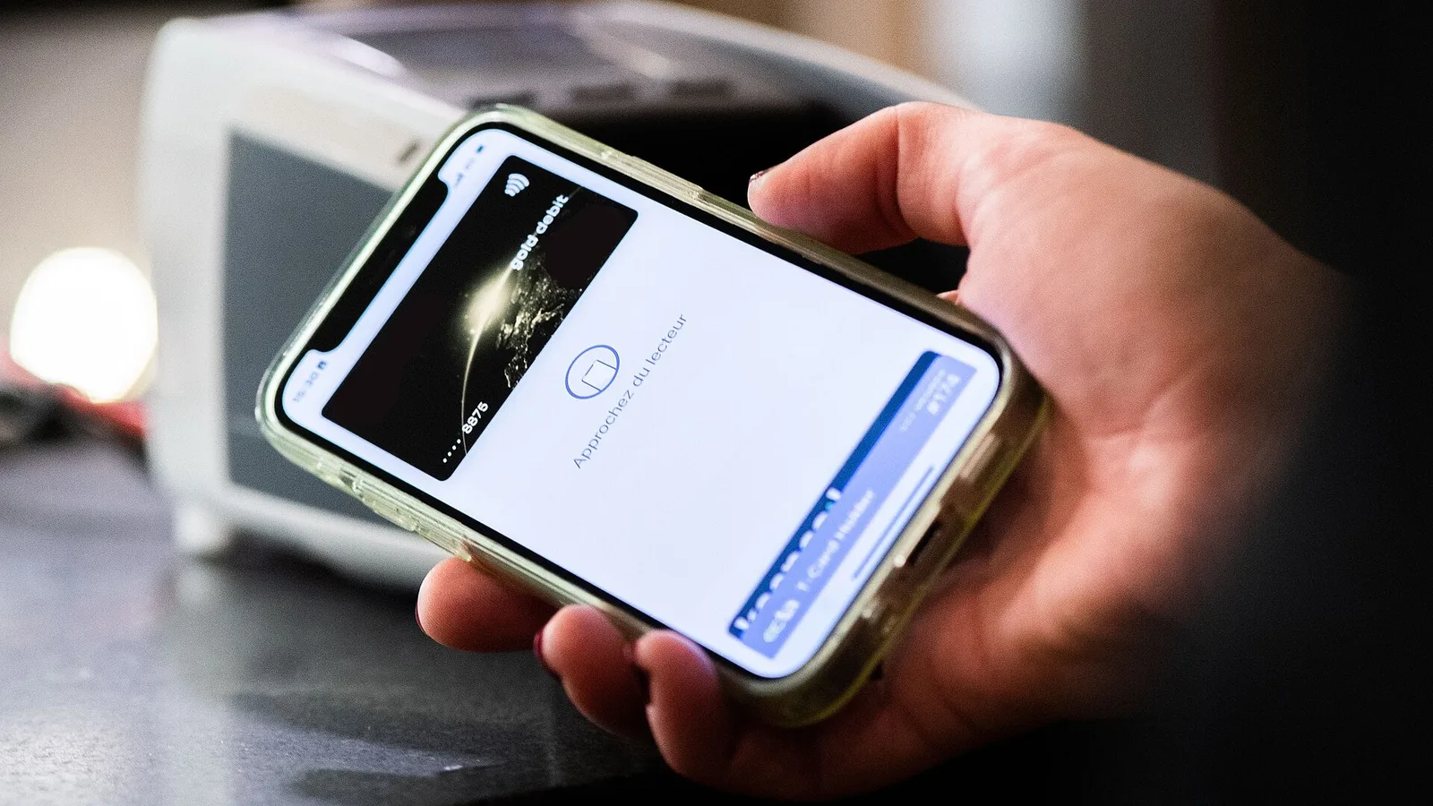 Pessoa aproxima o celular com a carteira digital aberta de uma maquininha para pagar por aproximação
