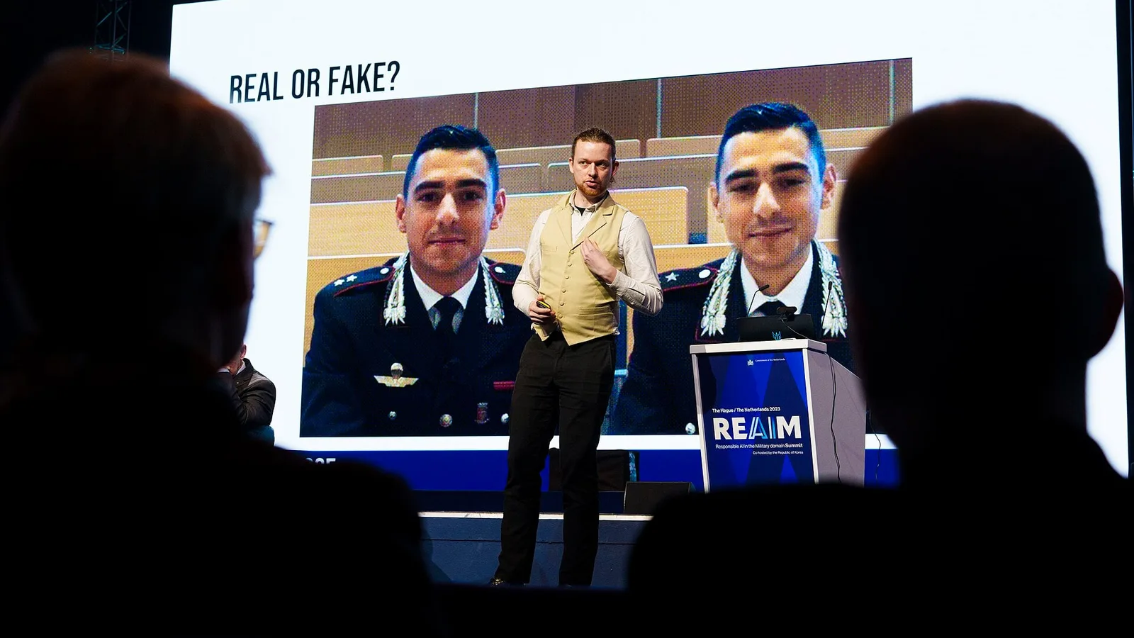 Plateia assiste a uma palestra com um slide que pergunta se a imagem projetada é real ou falsa