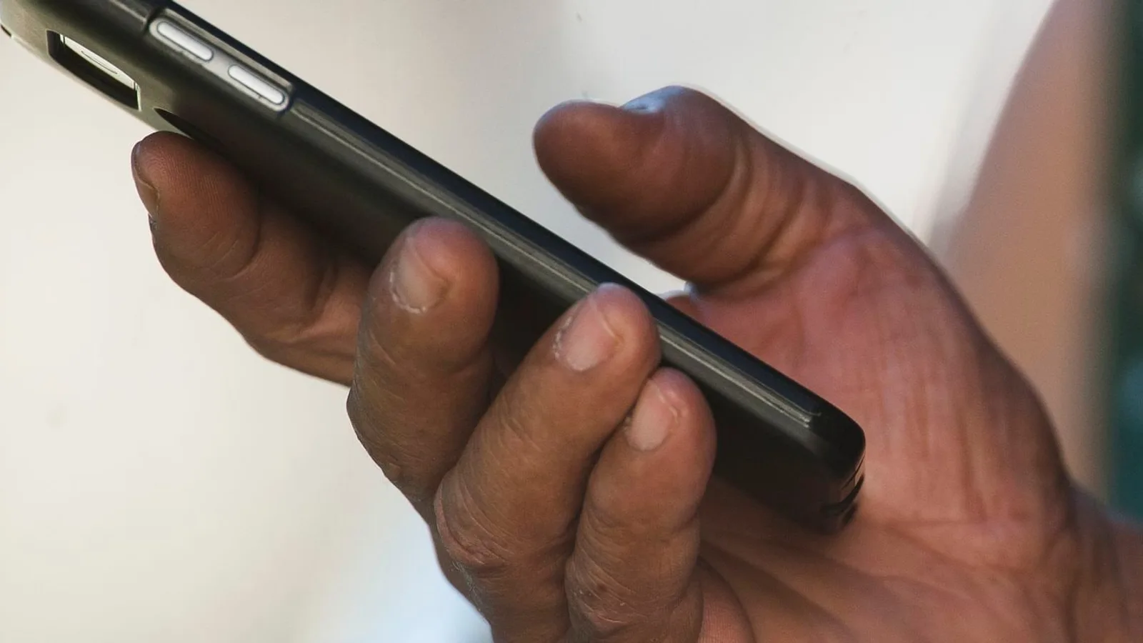 Mão segurando um smartphone, visto de lado
