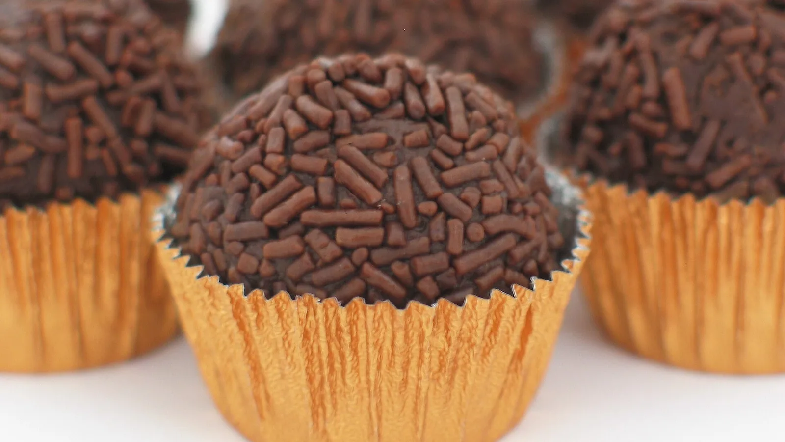Brigadeiros cobertos com granulado de chocolate em forminhas douradas