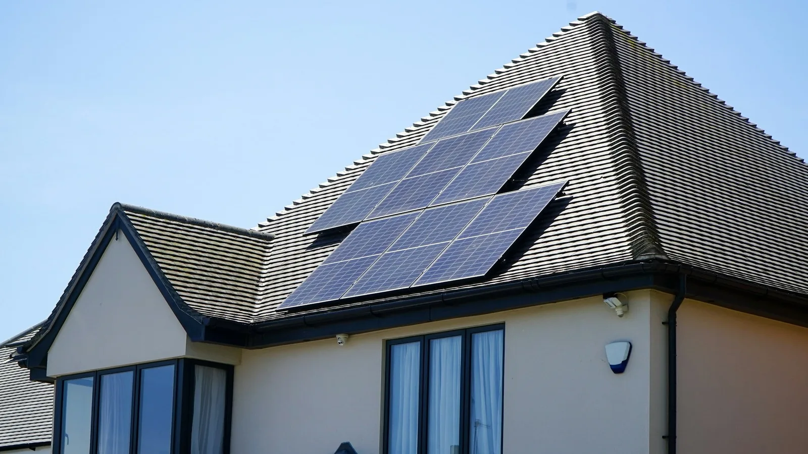 Casa com placas solares instaladas no telhado, sob céu azul