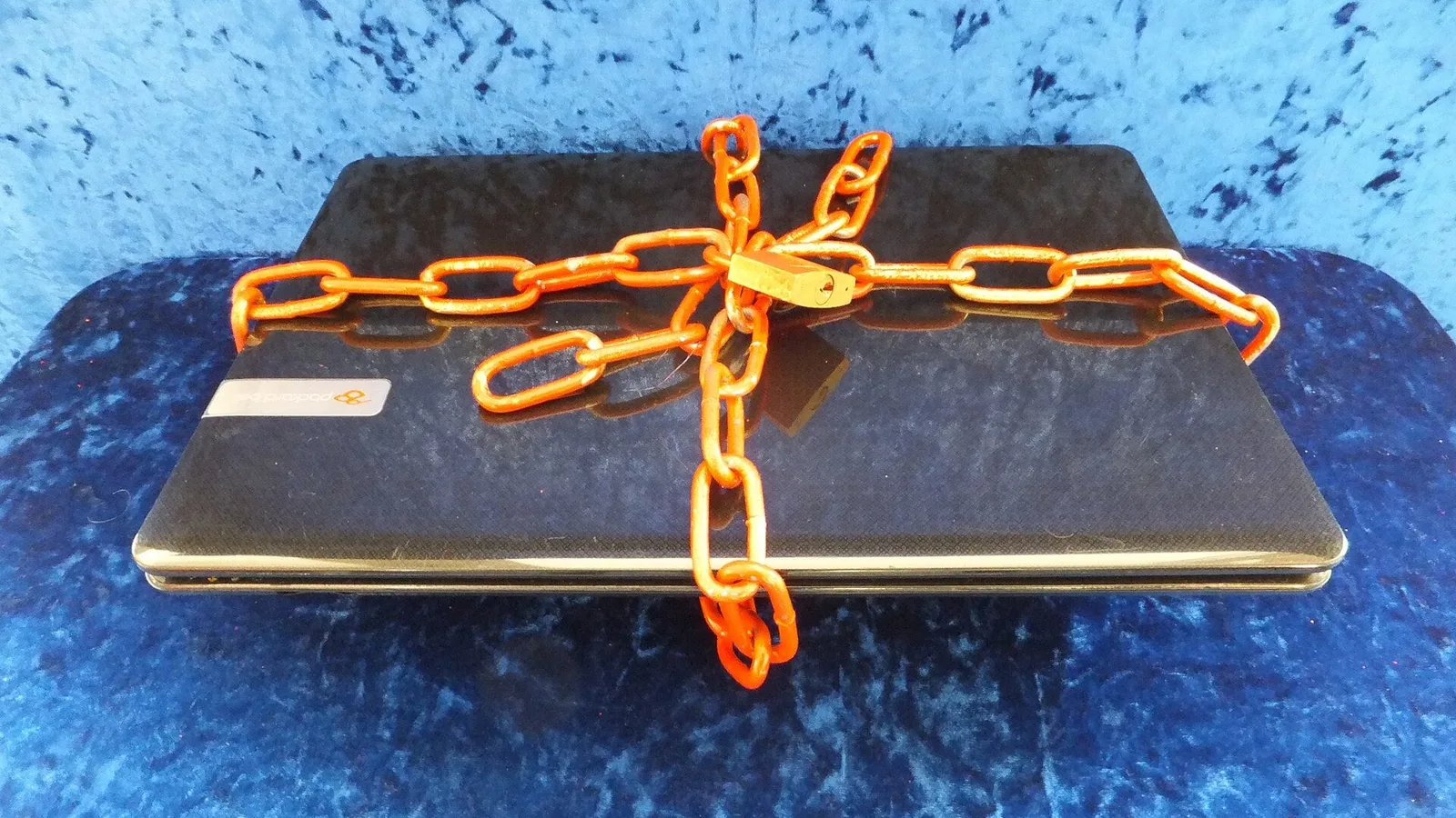Notebook fechado, envolto em correntes laranja e preso com um cadeado