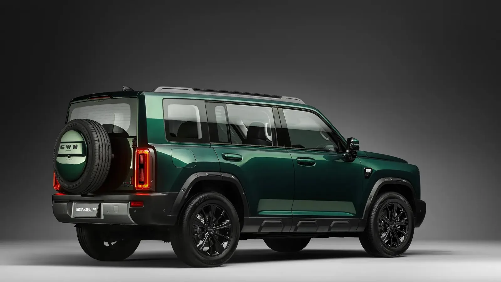 Haval H7 verde visto de trás e de lado, em estúdio, com estepe na tampa traseira