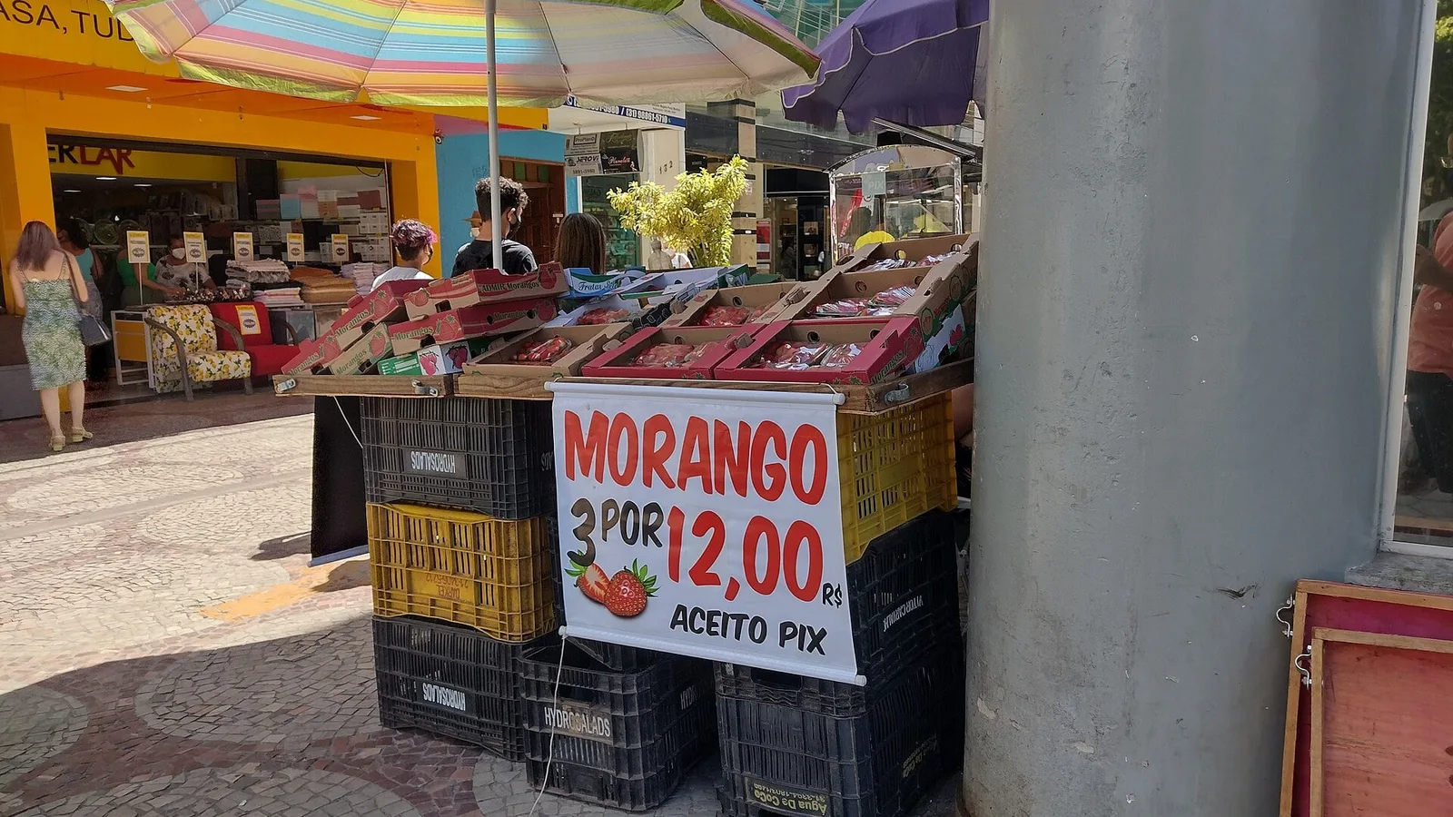 Barraca de rua vendendo morangos com placa de preço e o aviso Aceito Pix