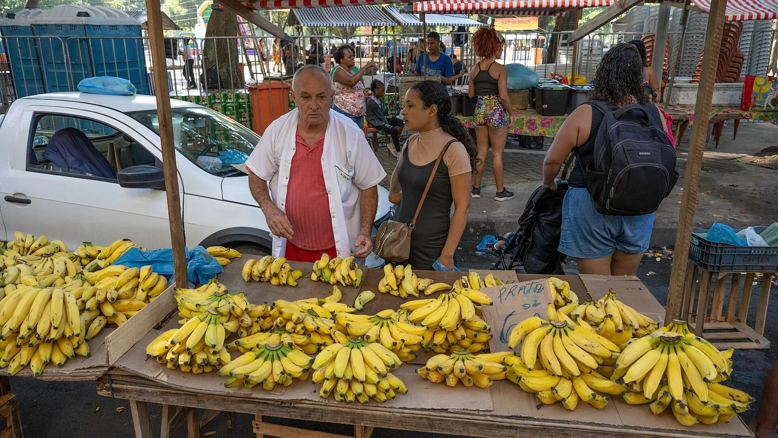 Feirante conversa com cliente em barraca de frutas numa feira de rua no Rio de Janeiro