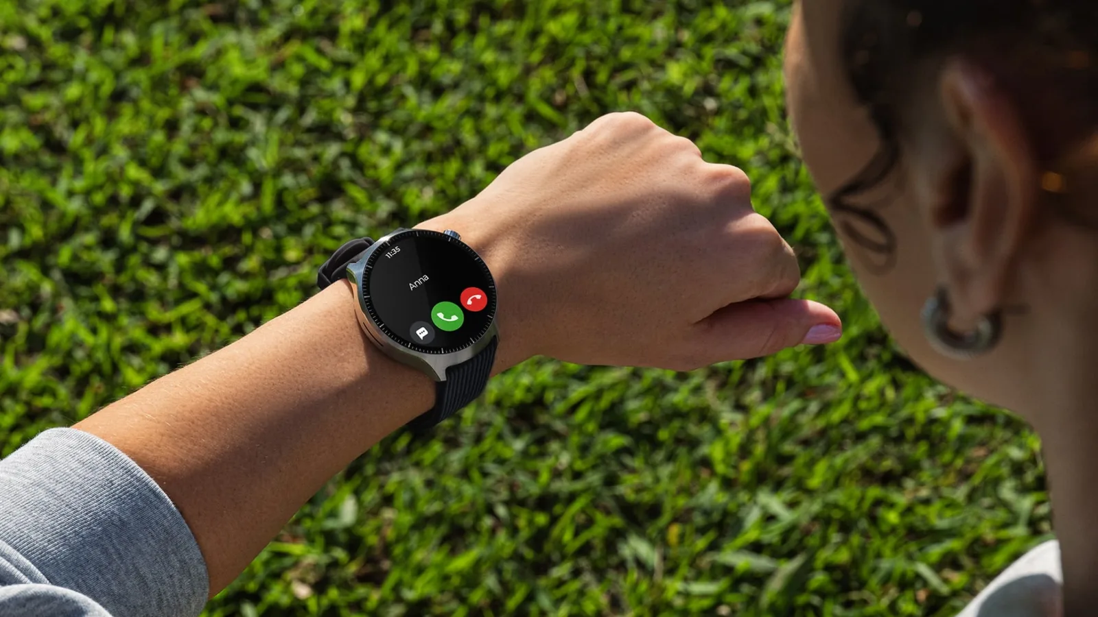 Pessoa atende uma chamada no Moto Watch Ultra, com caixa de aço e pulseira preta, ao ar livre