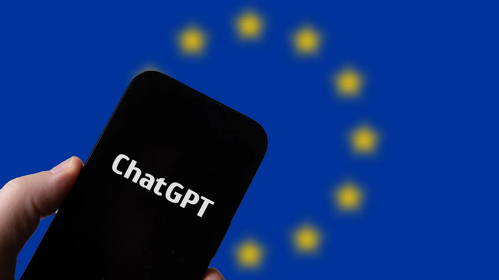 Mão segurando um celular com o ChatGPT aberto na frente da bandeira da União Europeia