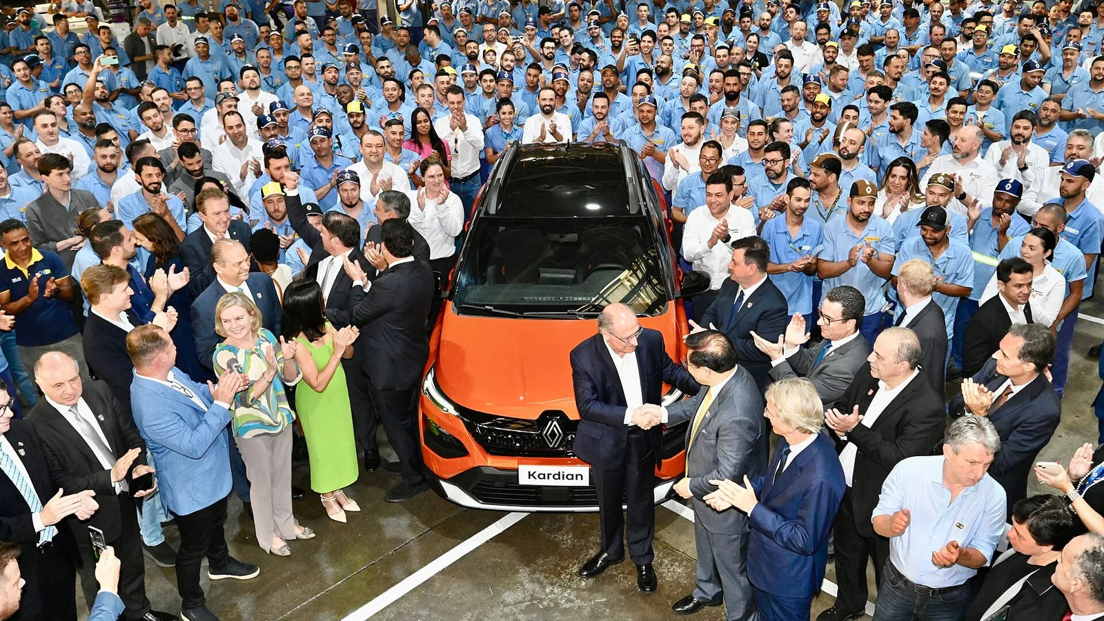 Funcionários reunidos em volta de um carro laranja na fábrica da Renault em São José dos Pinhais, no Paraná
