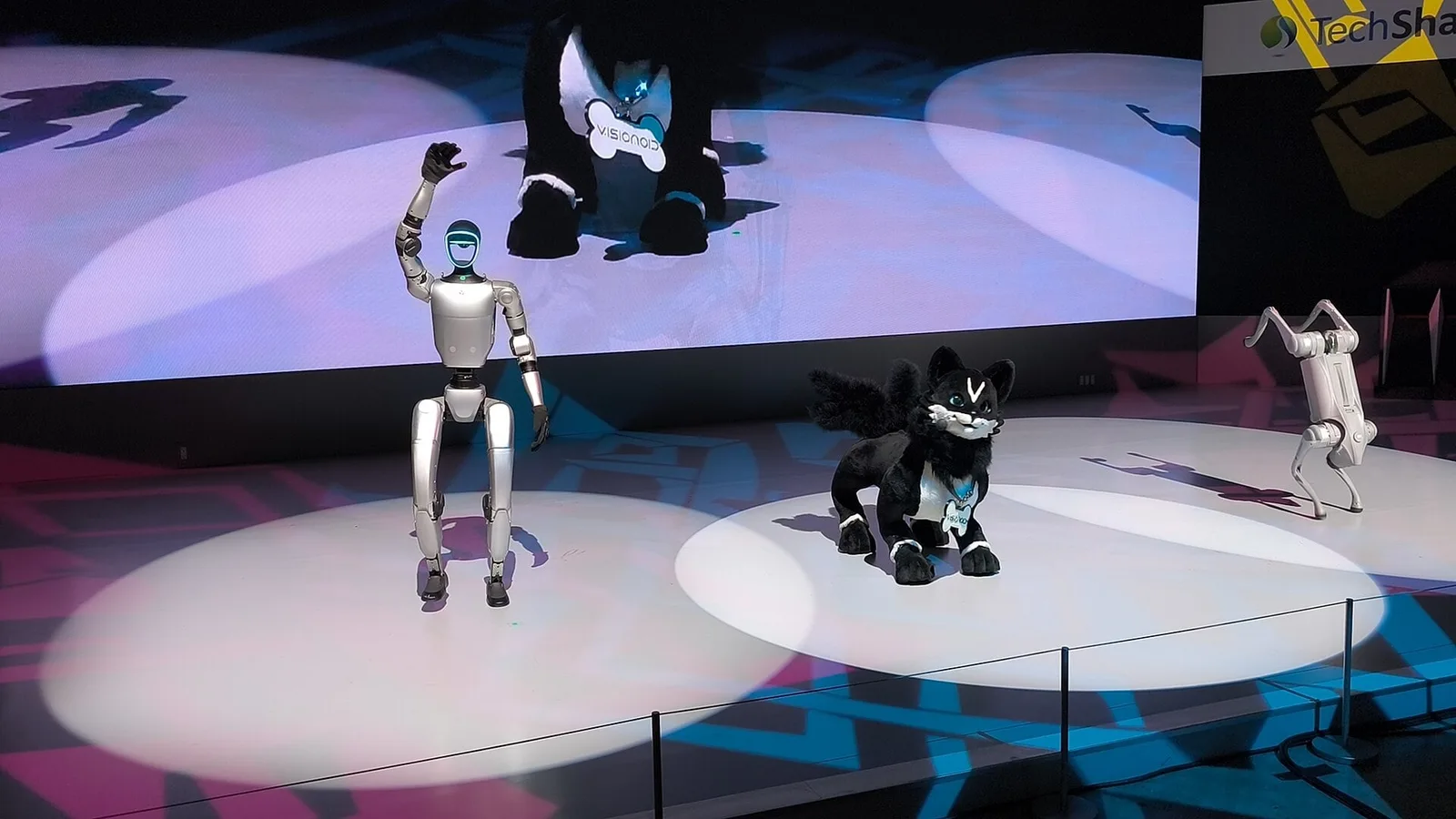 Robô humanoide Unitree G1 acena no palco do Japan Mobility Show 2025, em Tóquio, ao lado de outros robôs