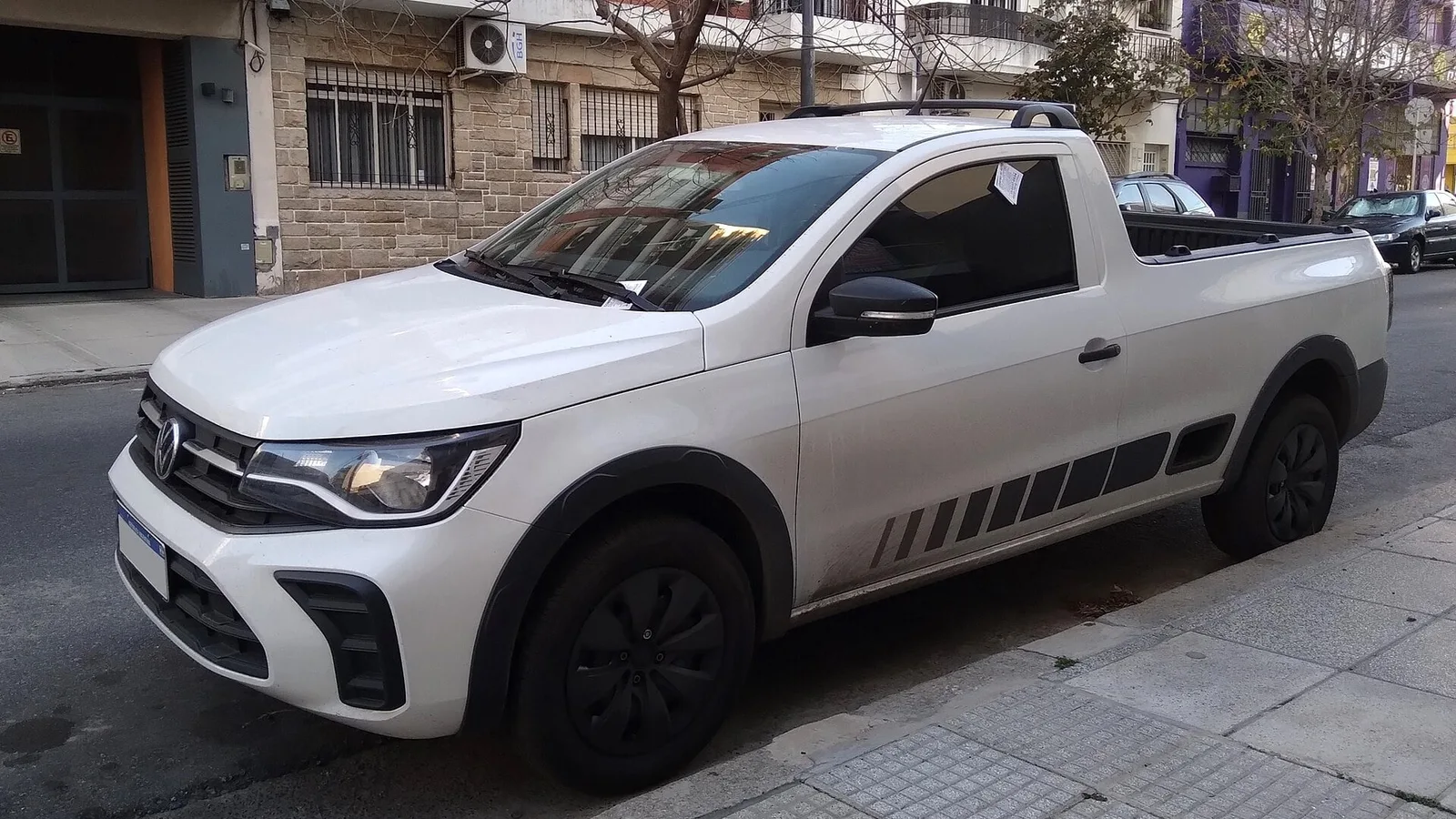 Volkswagen Saveiro branca de cabine simples estacionada na rua, vista dianteira e lateral