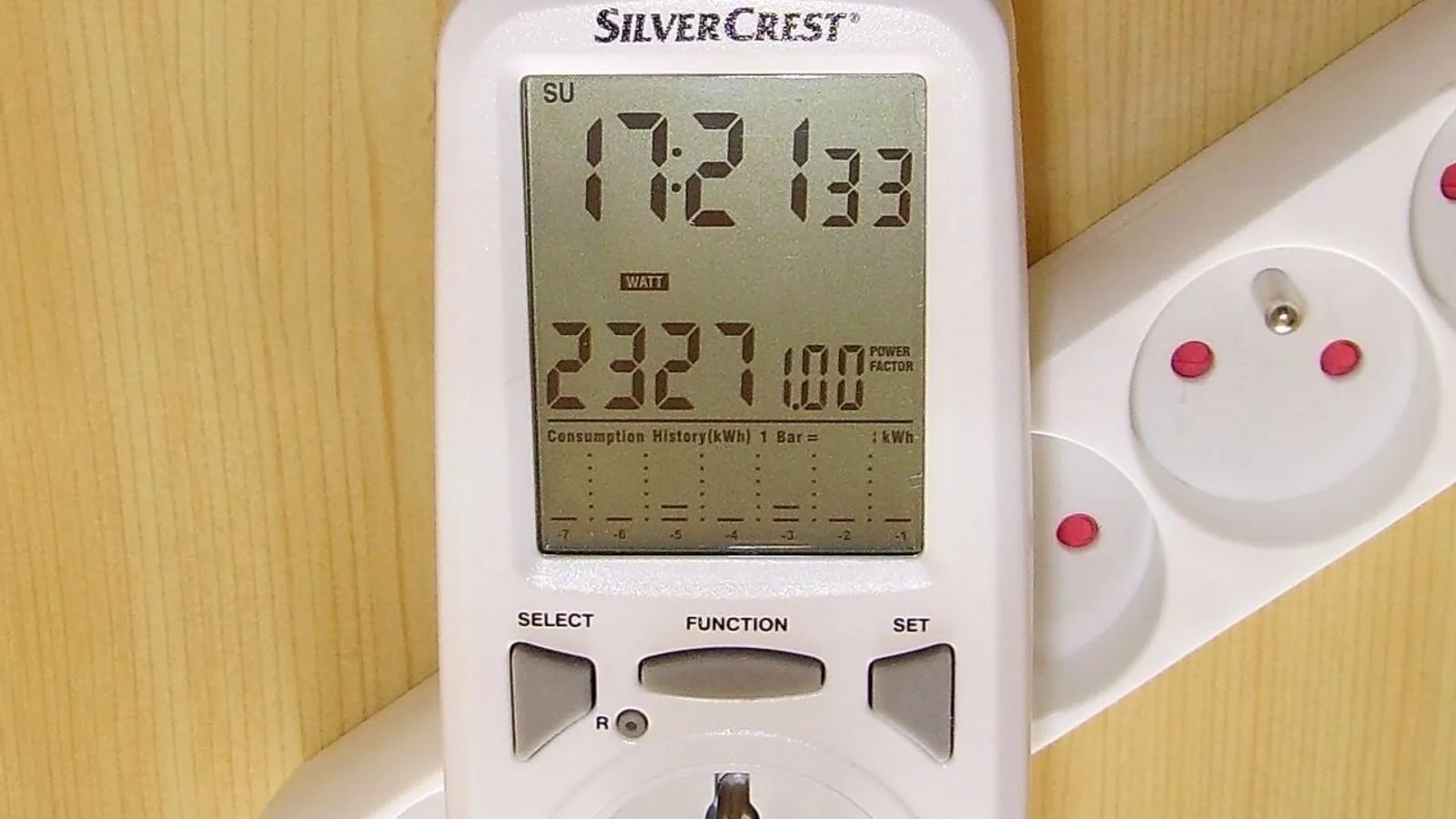 Medidor de consumo de energia de encaixe na tomada, com visor mostrando a potência em watts e o histórico em kWh