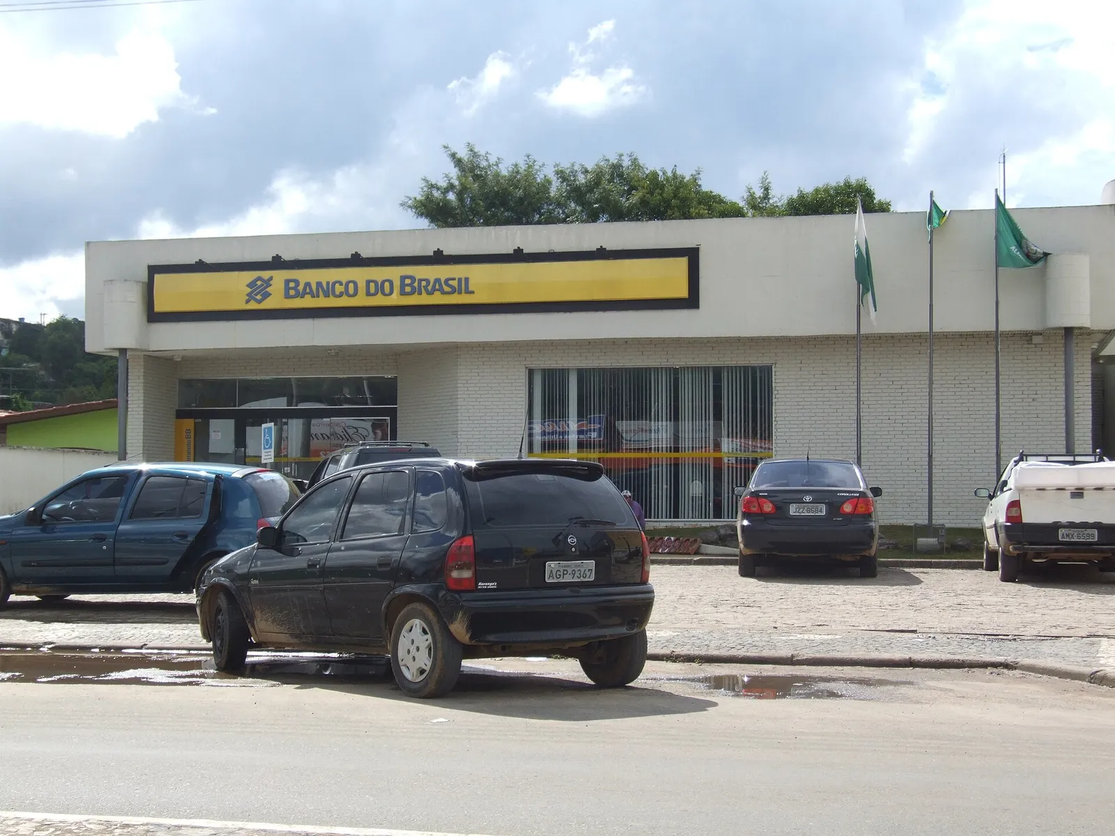 Fachada de uma agência do Banco do Brasil com carros estacionados em frente