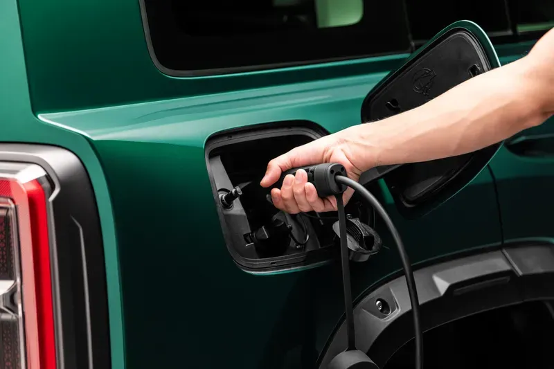 Mão conectando o plugue de recarga na lateral do Haval H7